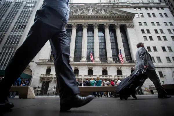 Pedestrians walk past the New York Stock Exchange (NYSE) stands in New York, U.S., on Friday, April 1, 2016. U.S. stock-index futures fell, tracking declines in crude oil, amid data showing job gains and higher wages that supported the case for raising interest rates. Photographer: Michael Nagle/Bloomberg