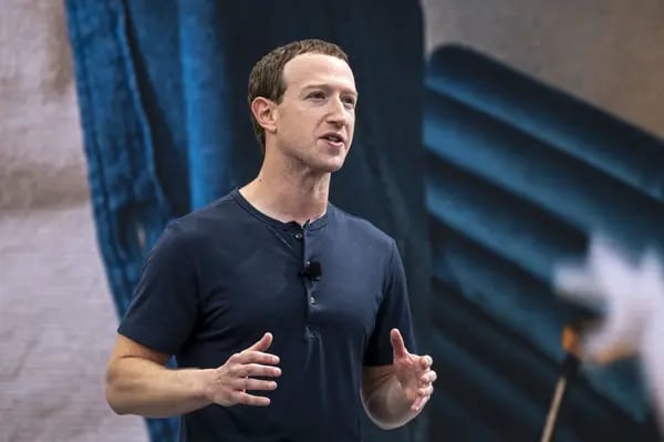 Mark Zuckerberg gesticulando. Ele é um homem branco e loiro e veste uma camiseta azul marinho