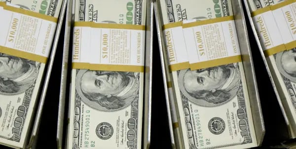 Pilas de billetes de cien dólares pasan por una máquina circuladora en la Oficina de Grabado e Impresión de Washington, D.C.