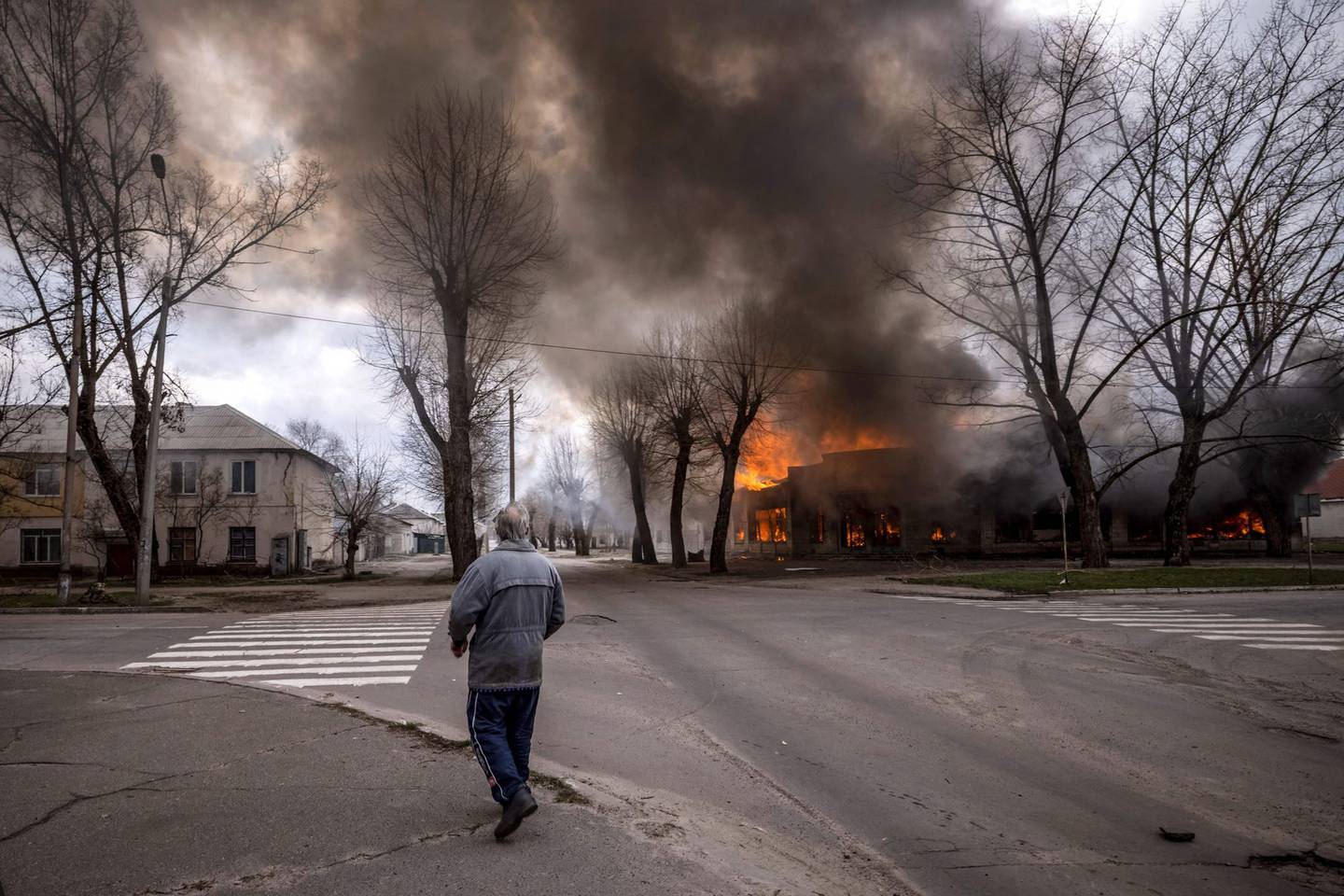Un hombre camina por una acera mientras una casa arde tras un bombardeo Severodonetsk, región de Donbass, el 6 de abril de 2022 Fotógrafo: Fadel Senna/AFP/Getty Images