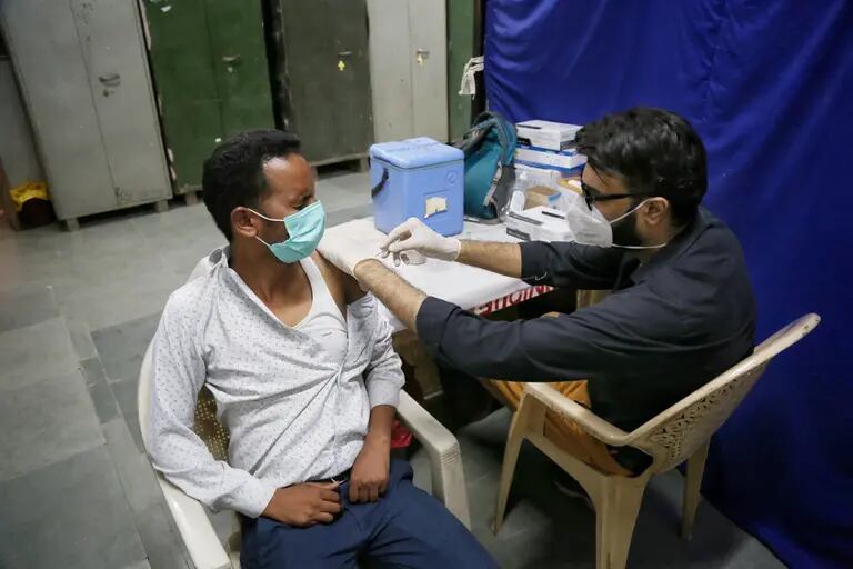 Um profissional de saúde administra vacina contra a Covid-19 em Nova Délidfd
