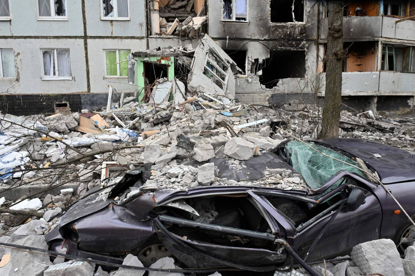 Carro destruído em frente a prédio em escombros no norte de Kharkiv