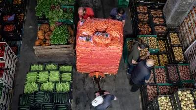 Trabajadores empujan un cargador de palets lleno de sacos de zanahorias dentro de un distribuidor en Oporto, Portugal.