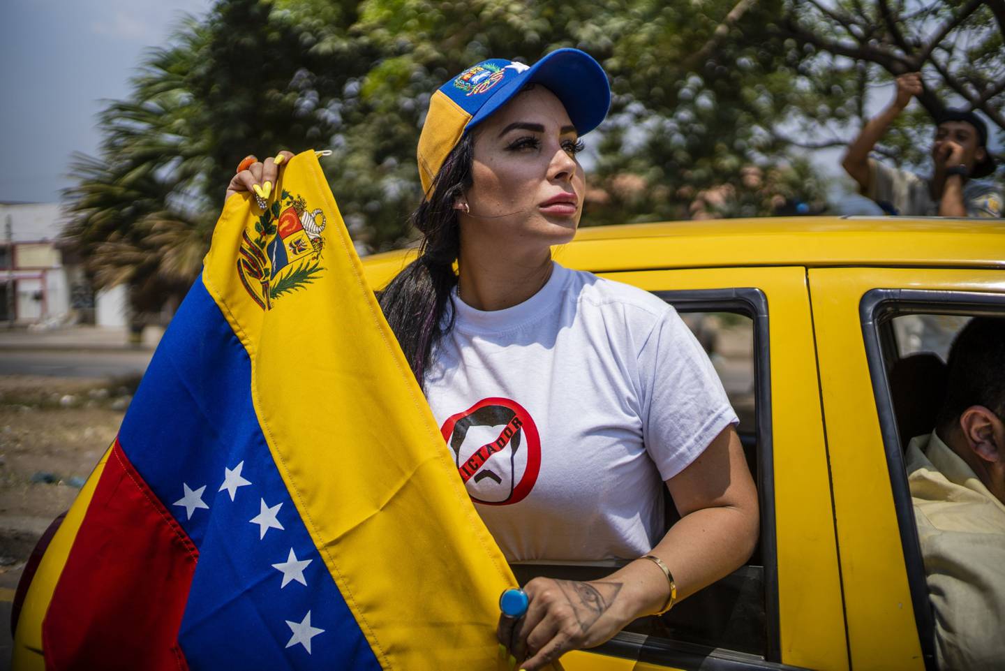 Un manifestante sostiene una bandera venezolana mientras conduce cerca del puente internacional Simón Bolívar en Cúcuta, Colombia, el sábado 23 de febrero de 2019.