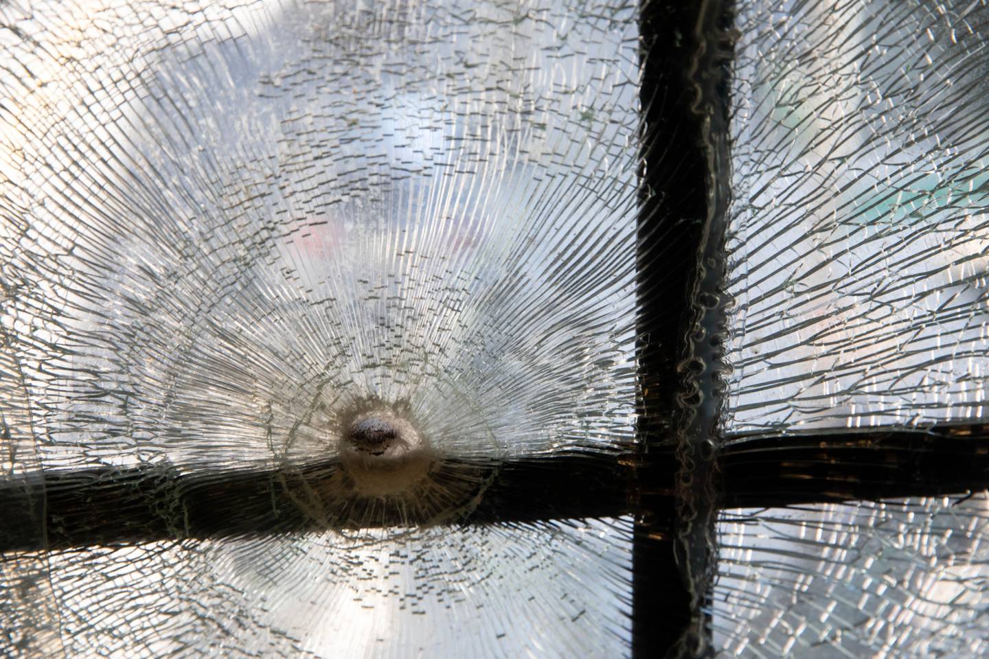 A bullet hole in a shattered window.