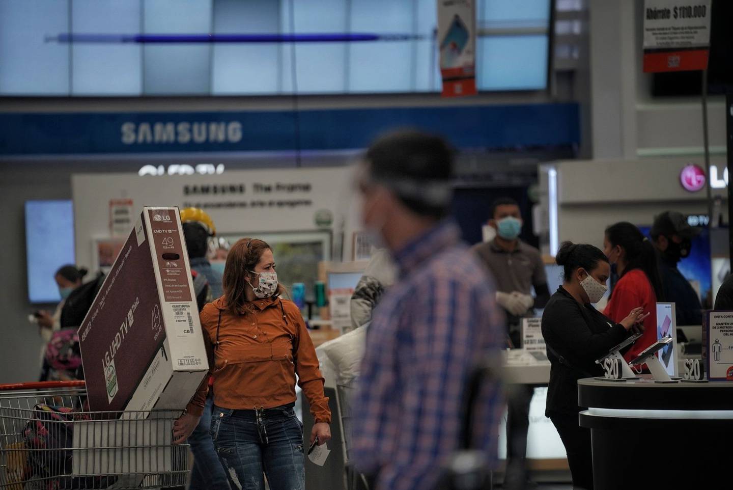 Los compradores con máscaras protectoras buscan productos electrónicos en una tienda Alkosto en Bogotá, Colombia, el viernes 19 de junio de 2020.dfd