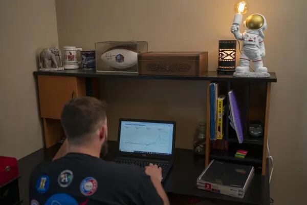 Kyle Walton mira su computadora portátil para revisar sus inversiones, realiza una investigación y revisa su grupo de Facebook desde su oficina en casa. @400northcreative / Doug Barrett