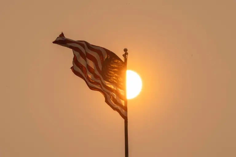A hazy sun illuminates an American flag as smoke from Canada wildfires blankets New York, US, on Wednesday, June 7, 2023. dfd