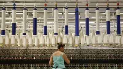 Los hilos de algodón cuelgan arriba mientras un empleado comprueba el hilado en la planta de procesamiento de Selected Textiles S.A. en Farsala, Grecia, el viernes 10 de julio de 2015.