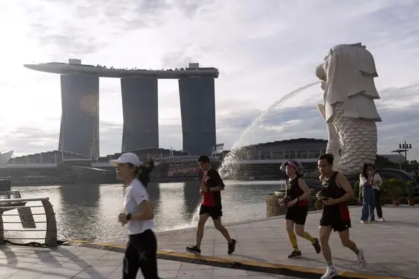 Foto de pessoas correndo em frente a uma fonte em Singapura