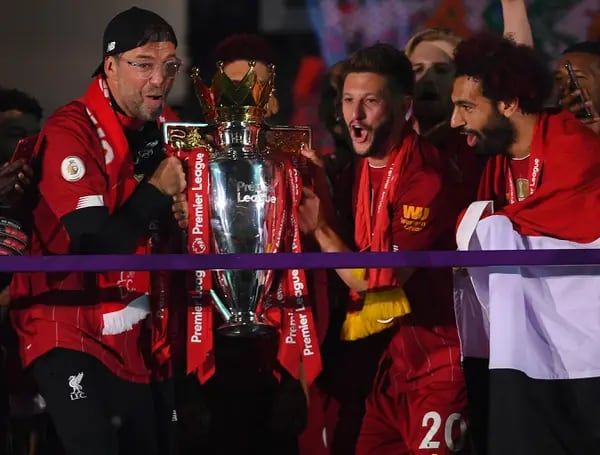 Jurgen Klopp, Adam Lallana y Mohamed Salah, del Liverpool, sostienen el trofeo de la Premier League para celebrar la obtención del título de liga durante la ceremonia de presentación del partido de la Premier League entre el Liverpool FC y el Chelsea FC en Anfield el 22 de julio de 2020 en Liverpool, Inglaterra.