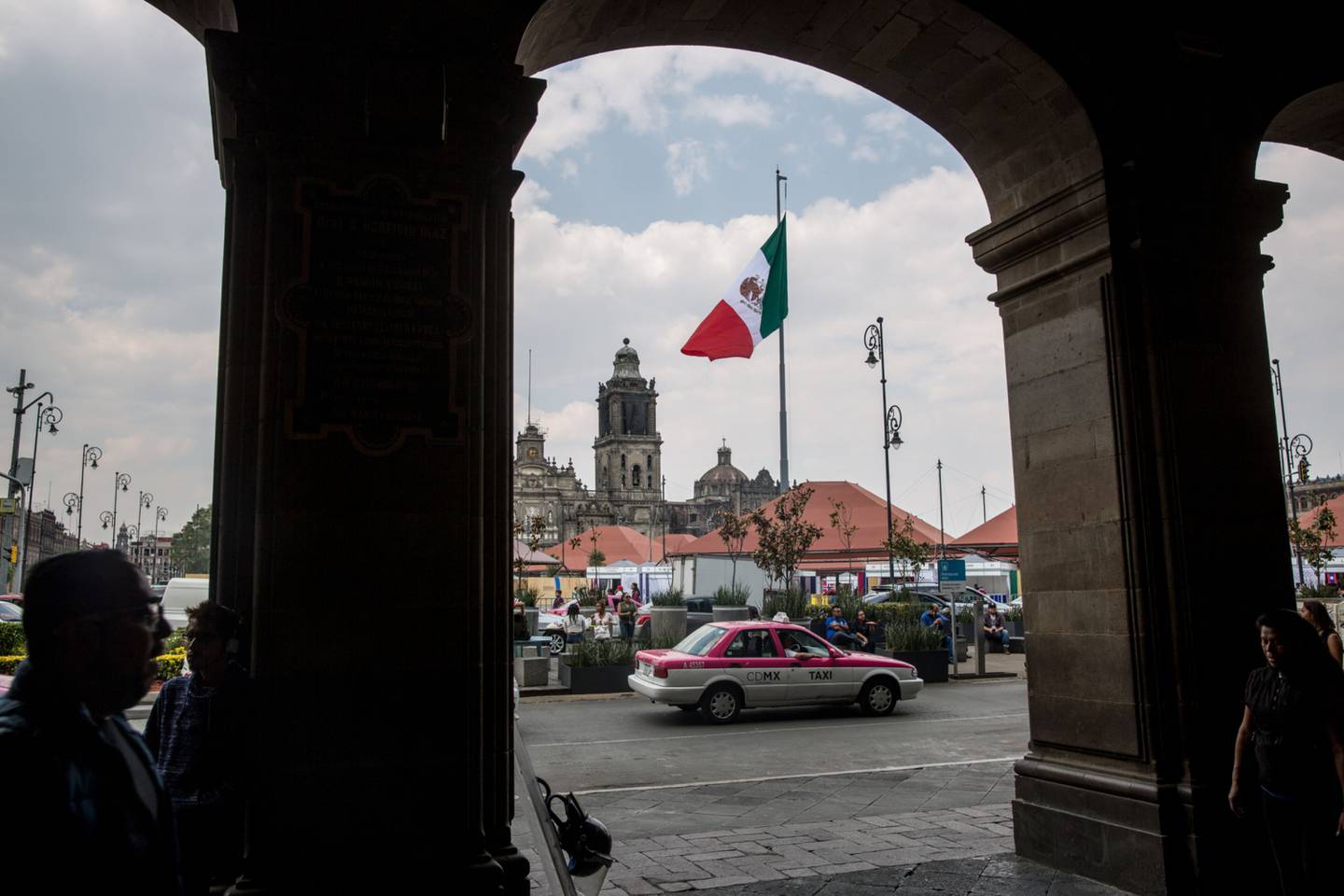 Un taxi pasa frente a la bandera mexicana que ondea en la Plaza de la Constitución (Zócalo) en la Ciudad de México, México, el viernes 13 de abril de 2018.