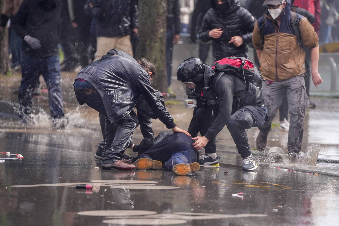Protesters assist a person on the ground as water cannons are fired to disperse crowds during a demonstration against pension reform in central Paris, France, on Monday, May 1, 2023. Photographer: Nathan Laine/Bloombergdfd