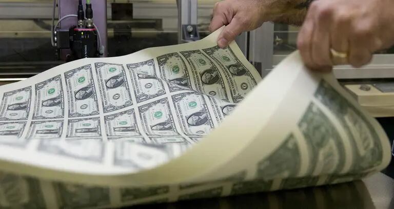 Un prensista airea una pila de billetes de US$1 de 2017 sin cortar en la Oficina de Grabado e Impresión de EE.UU., en Washington, D.C.dfd