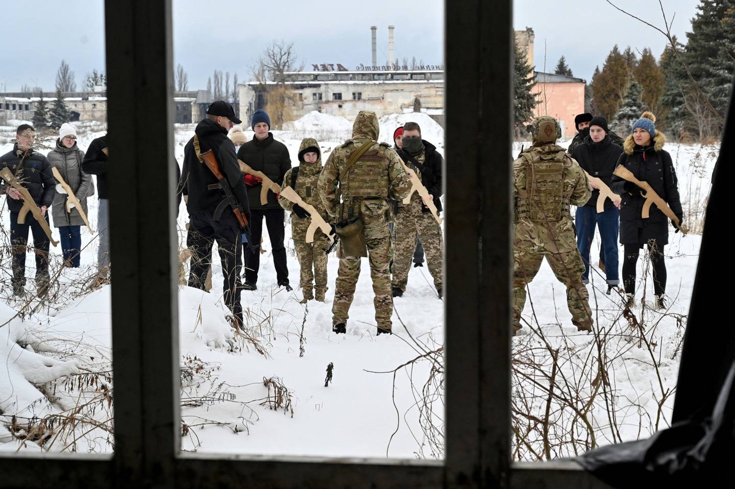 Un instructor militar enseña a civiles que sostienen réplicas de madera de rifles Kalashnikov durante un entrenamiento