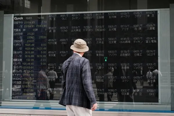 Un peatón mira un tablero electrónico que muestra acciones sin precios fuera de una empresa de valores en Tokio, Japón, el jueves 1 de octubre de 2020. Fotógrafo: Soichiro Koriyama/Bloomberg