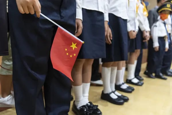 Un estudiante sostiene la bandera nacional china durante una ceremonia en la Escuela Secundaria de Fukien para celebrar el Día Nacional en Hong Kong, China, el viernes 1 de octubre de 2021.