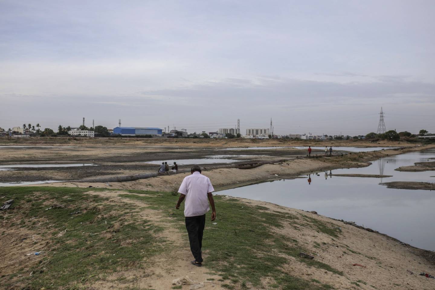 A man walks across the bottom of the dried-out Porur Lake during a drought in Chennai, India, July 5, 2019.  Photographer: Dhiraj Singh/Bloombergdfd