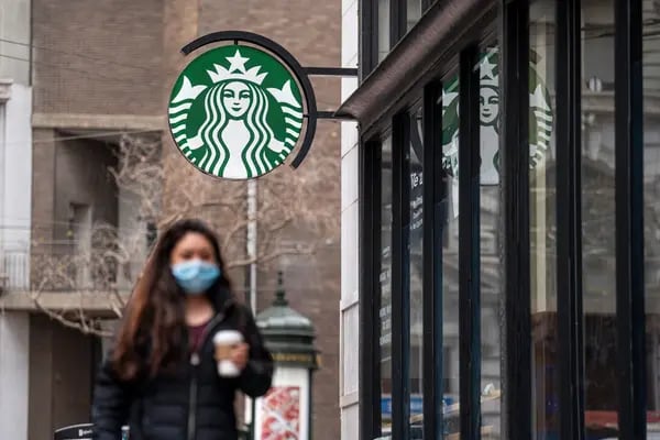 Una persona con una mascarilla pasa por delante de una cafetería Starbucks en San Francisco, California.