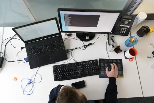 Un empleado utiliza un ordenador de sobremesa y un portátil en una estación de trabajo en las oficinas de Luxoft Holding Inc. en Kiev, Ucrania, el martes 31 de octubre de 2017.