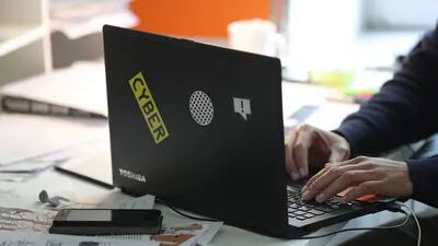 Un empleado utiliza un portátil Toshiba Corp. decorado con una pegatina "Cyber".