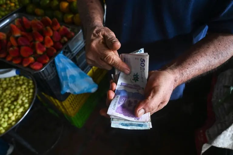 Un vendedor cuenta billetes de pesos colombianos en un mercado de Cali, Colombia. Fotógrafo: Joaquín Sarmiento/AFP/Getty Imagesdfd