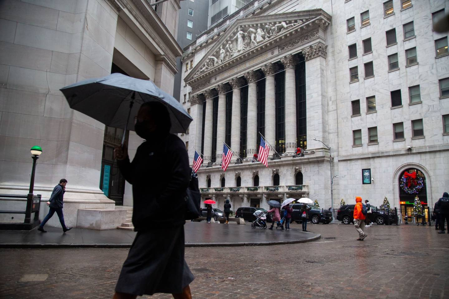 Peatones llevan paraguas frente a la Bolsa de Nueva York (NYSE) en Nueva York, EE.UU., el martes 3 de enero de 2023.