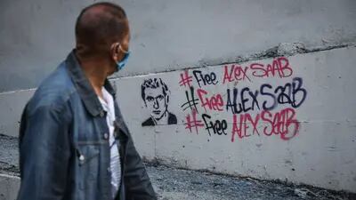 Un peatón pasa junto a una graffitti en Caracas de apoyo al empresario Alex Saab.