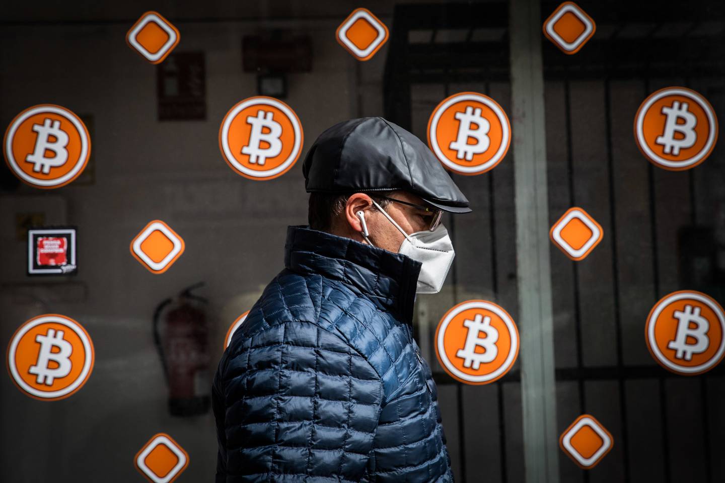 Un peatón con una máscara protectora pasa por un quiosco de cajeros automáticos de bitcoin en Barcelona, España.