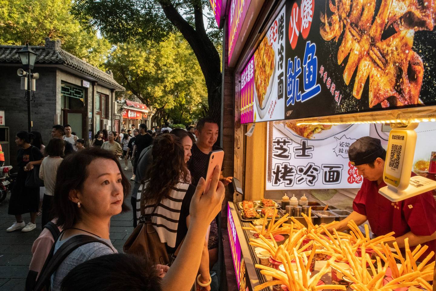 A woman uses a digital payment service to buy food in Beijing on Aug. 12.dfd