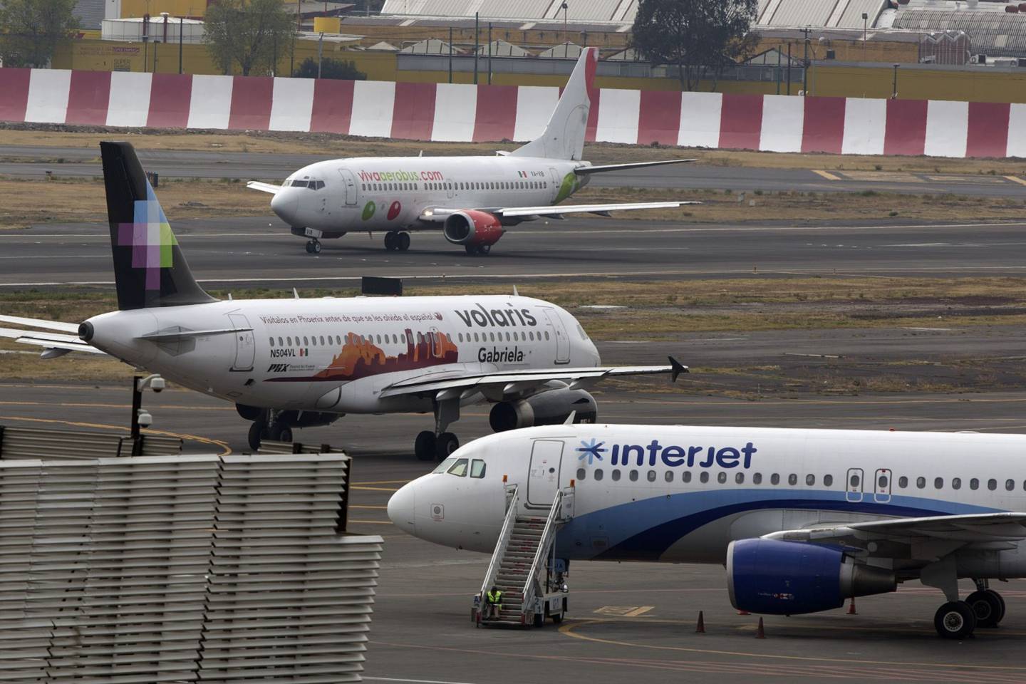 Interjet and Volaris airplanes sit parked on the tarmac while a Grupo Viva Aerobus SAB airplane prepares to take off at Benito Juarez International Airport (AICM) in Mexico City, Mexico, on Thursday, Jan. 16, 2014. Grupo Viva Aerobus SAB filed for what would be Mexico's second initial public offering of shares by an airline since September as passenger traffic sets annual records. Interjet, Mexico's second-biggest carrier in 2012, may sell shares this year, Executive President Miguel Aleman Magnani said in November. Photographer: Susana Gonzalez/Bloomberg