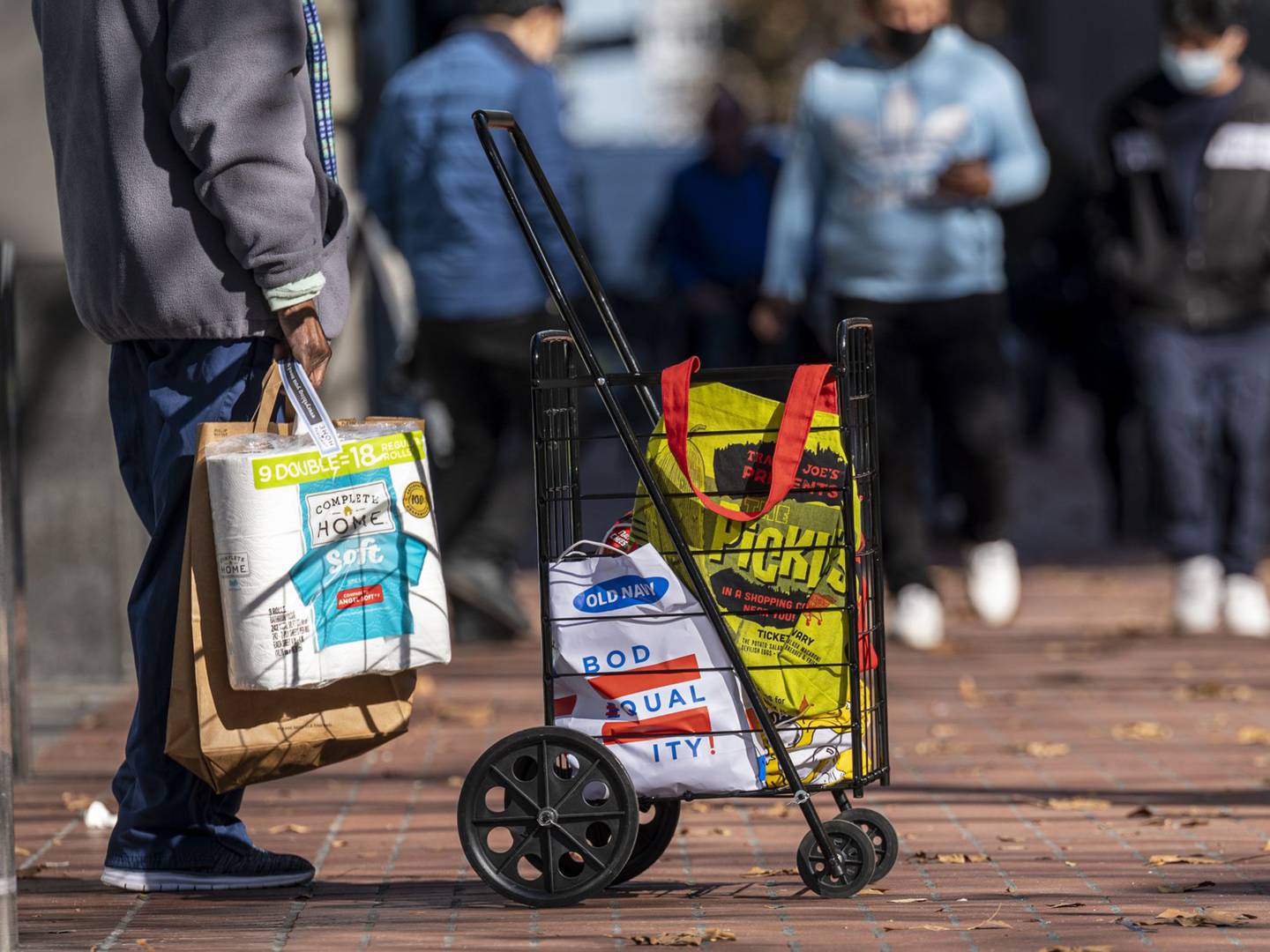 Un viajero lleva sus compras mientras espera el autobús en la calle Market de San Francisco, EE.UU.