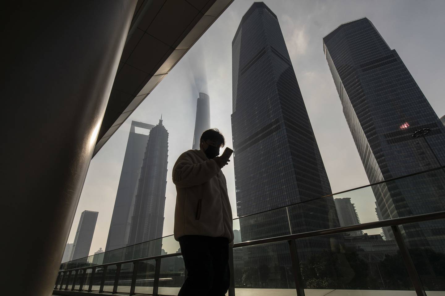 Un peatón pasa por delante de los edificios del distrito financiero de Lujiazui, en Shanghai.