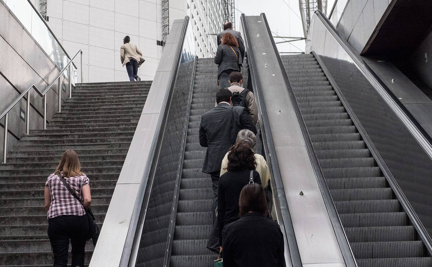 Viajeros suben por una escalera y se desplazan por una escalera mecánica a su llegada al distrito financiero de La Defense, en París.