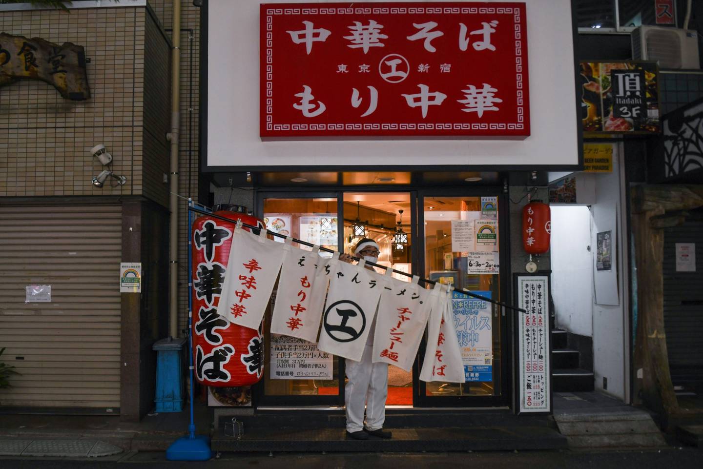Un trabajador quita un cartel de un bar de ramen en Tokio, Japón.