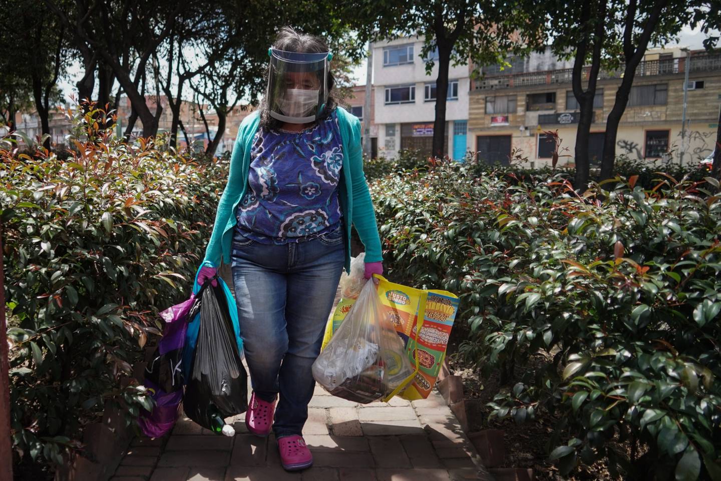Una mujer con una máscara protectora llega a su casa después de abastecerse en Bogotá, Colombia, el martes 14 de abril de 2020.dfd