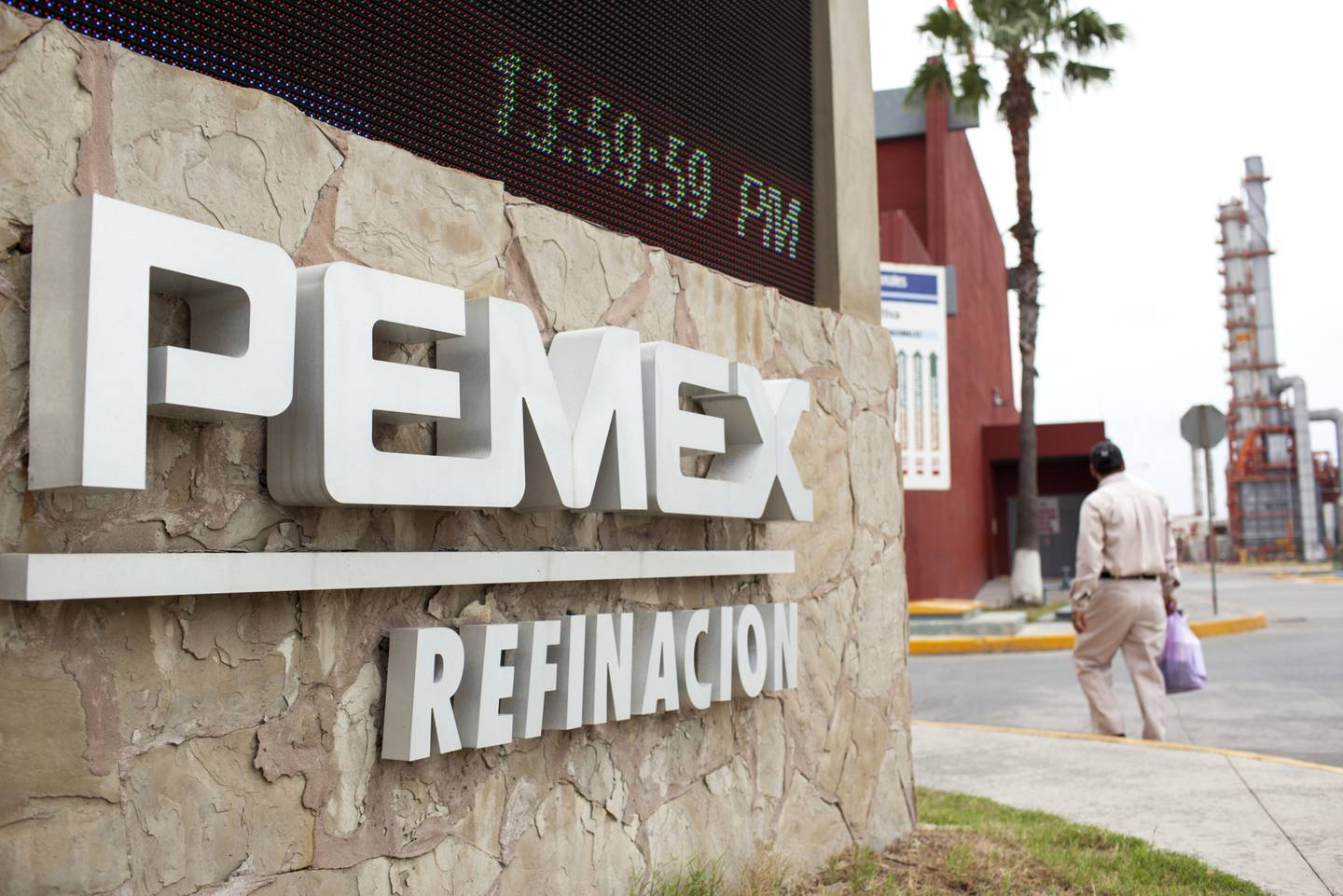 A worker walks past signage at the Petroleos Mexicanos (Pemex) refinery in Cadereyta, Mexico, on Thursday, April 7, 2016. The Mexican government expects oil output of 2.12 million barrels per day this year, according to a Finance Ministry report to congress earlier this month. Photographer: Brett Gundlock/Bloomberg