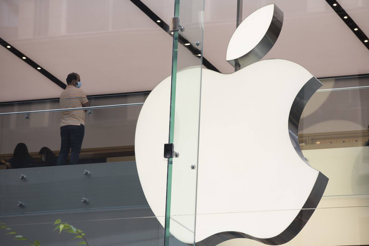 A customer stands near an Apple Inc. logo at a store in Sydney, Australia, on Monday, Feb. 28, 2022. Australia is scheduled to release gross domestic product (GDP) figures on March 2. Photographer: Brent Lewin/Bloomberg