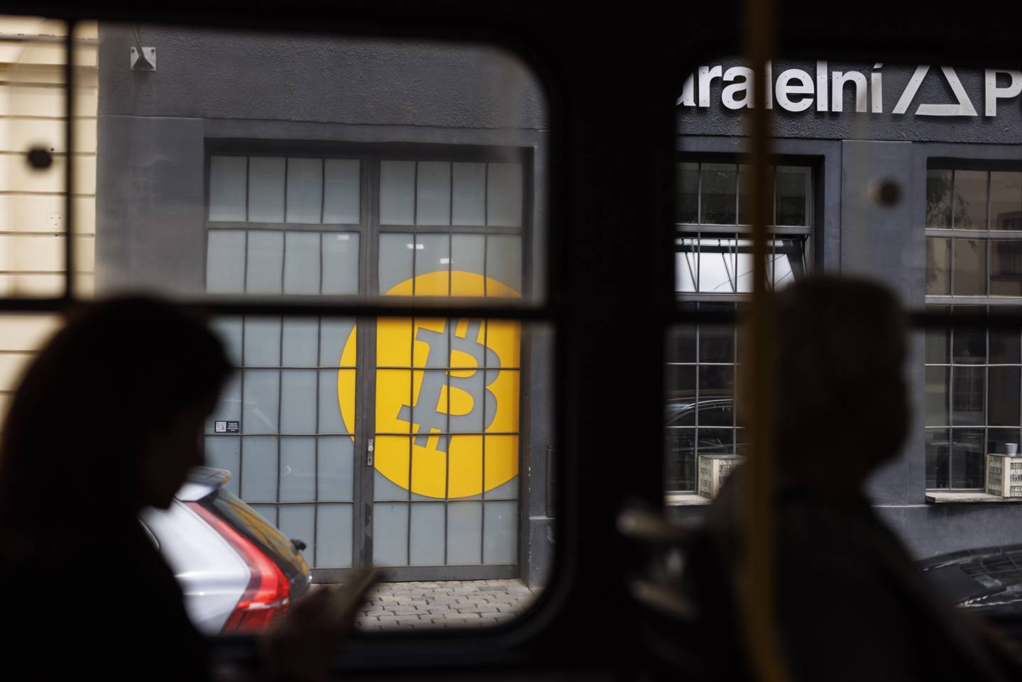 Pasajeros en un tren pasasn un logo de bitcoin en la puertas de Paralelni Polis  una organización que combina arte, ciencias sociales y  tecnología moderna en Praga, República Chea el marte 17 de mayo. Fotógrafo: Milan Jaros/Bloomberg