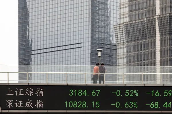Pedestrians along an elevated walkway as an electronic ticker displays stock figures in Pudong's Lujiazui Financial District in Shanghai, China, on Friday, May 26, 2023. The cost of 12-month interest-rate swaps, which anticipate where interest rates will be in a years time, slipped to 2.06% this week, down from as high as 2.47% just over two months ago. Photographer: Qilai Shen/Bloomberg