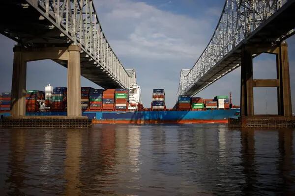 Um navio porta-contêineres passa sob a ponte Crescent City Connection perto do porto de Nova Orleans