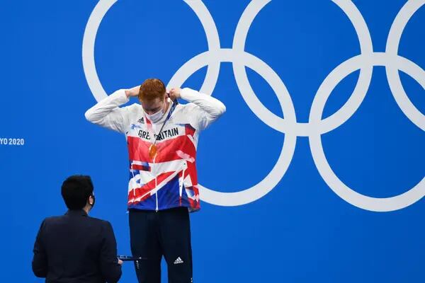 El nadador británico Tom Dean se coloca una medalla de oro tras ganar la competencia de 200 metros de nado libre en Tokio 2020.