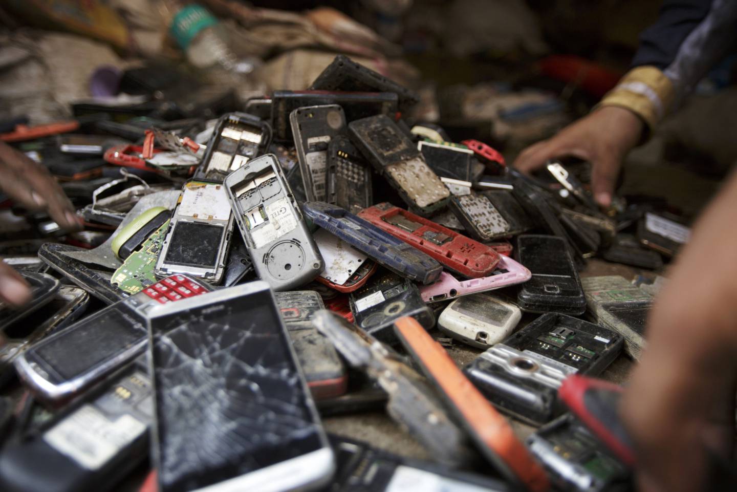 Los trabajadores revisan una pila de teléfonos móviles usados ​​en Nueva Delhi, India.