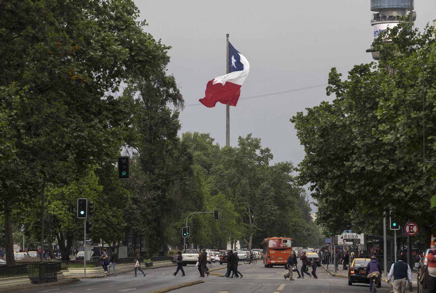 La bandera chilena ondea mientras los peatones cruzan una carretera en Santiago, Chile, el sábado 15 de octubre de 2016. Fotógrafo: Luis Enrique Ascui/Bloombergdfd