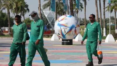 Workers pass a model of the Adidas official FIFA World Cup 2022 'Al Rihla' ball.