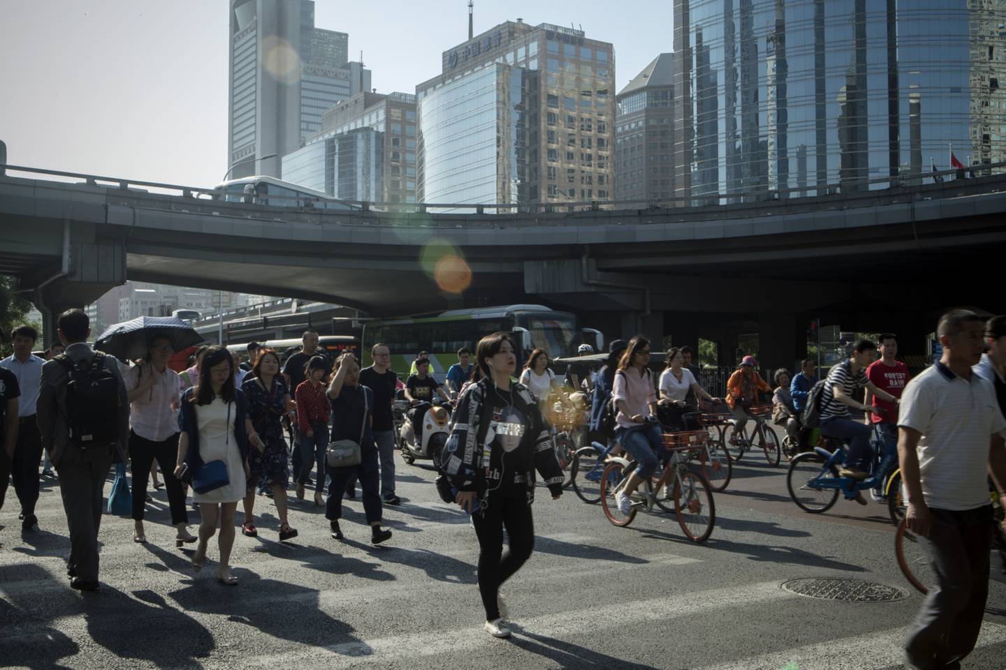 Peatones cruzan una calle junto a ciclistas y otros vehículos en el distrito central de negocios en Beijing, China, el viernes 1 de junio de 2018.