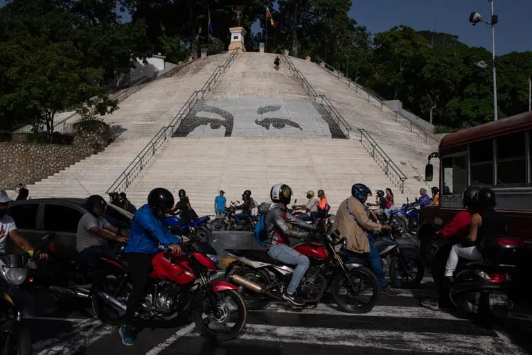 Motociclistas pasan frente a las escaleras del Calvario con la imagen de los ojos de Chávez de fondo.Fotógrafo: Gaby Oraa/Bloombergdfd
