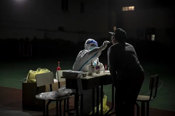 Un trabajador recoge una muestra de hisopo de un residente para una prueba de Covid-19 en un vecindario bajo cierre en Shanghai, China.