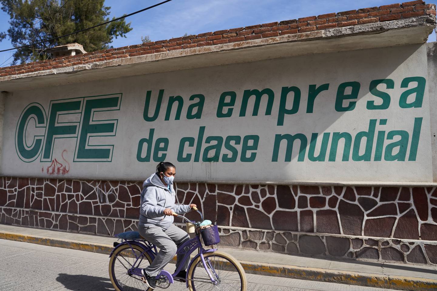 Una persona que usa una mascarilla protectora pasa en bicicleta frente a las instalaciones de la Comisión Federal de Electricidad (CFE) en Villa de Reyes, San Luis Potosí, México , el martes 19 de enero de 2021. 