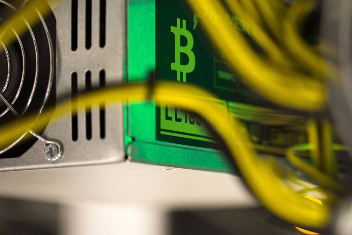 A bitcoin logo sits on a LL 1800W power unit supplying cryptocurrency mining machine.